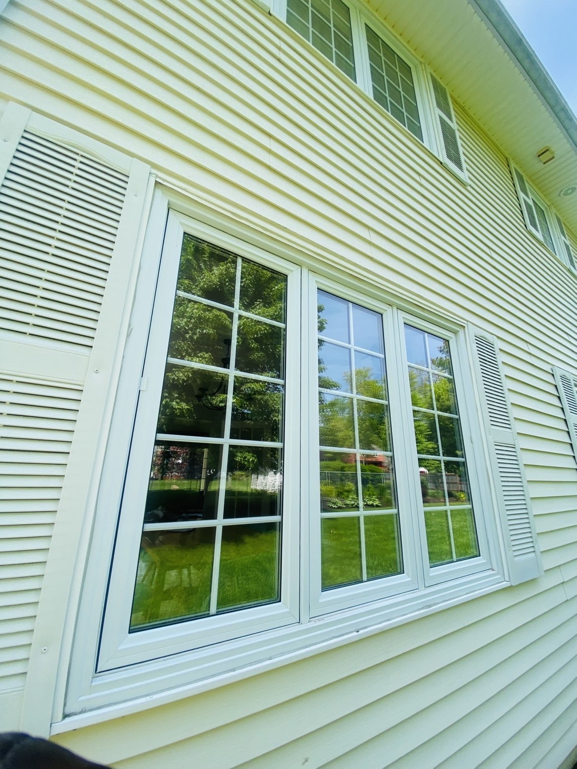 Freshly cleaned side windows on a two-story home reflecting trees and sky